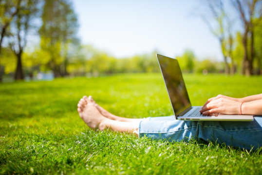 Working on laptop sitting on fresh turf
